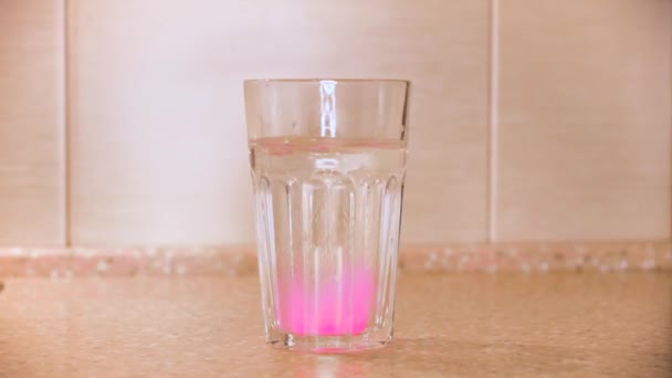 Close-up van de groene tablet voor het bereiden van zelfgemaakt mineraalwater in een glas water dat tegen de muur op tafel wordt geplaatst. Concept. Vruchtengearomatiseerde koolzuurhoudende drank. — Stockvideo