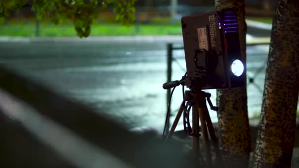 Прожектор запалює промінь для показу фото- та відеоматеріалів на вулиці вночі на порожньому дорожньому тлі. Мистецтво. Відеопроектор і штатив на відкритому повітрі в місті . — стокове відео