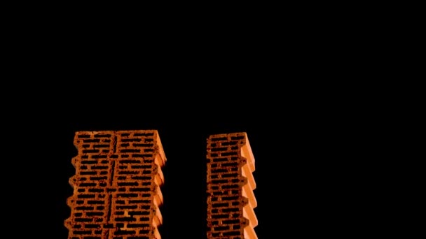 Nieuwe bouwmaterialen, rode bakstenen met gaten geïsoleerd op zwarte achtergrond. Voorraadbeelden. Close up van geperforeerde bakstenen die tegen een zwarte muur staan. — Stockvideo