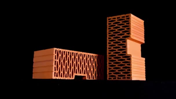 黒の背景に隔離された動き丸い穴を持つオレンジ色の穿孔レンガの閉じます。ストック映像だ新しいレンガ造りの家の建物のための材料. — ストック動画