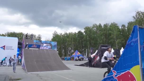 Yekaterinburg,ロシア- 8月, 2019:ライダーはフリースタイルショーでスタントを実行します。行動だ。プロの若いサイクリストがフェスティバルでランプからトリックを実行します。自転車に乗っている若い男がランプで飛んでいる — ストック動画