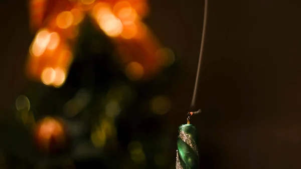 Närbild av ett släckt ljus med stigande rök på suddig bakgrund med dekorerad julgran. Begreppet. Vintersemester, grönt ljus med rökridå. — Stockfoto