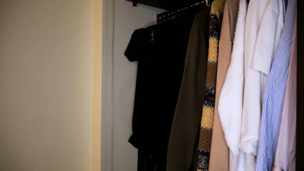 Close up of clothes in wardrobe near white wall. Concept. Side view of different shirts in full closet, details of apartment interior. — Stock Photo, Image