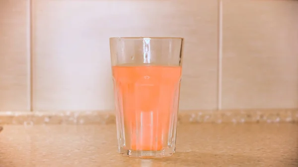 Primer plano del vaso de agua y una tableta efervescente, primer plano. Concepto. Píldora analgésica naranja redonda, concepto médico, vitaminas solubles en agua . — Foto de Stock