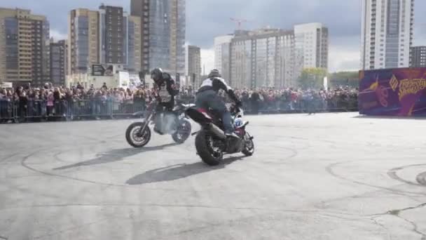 Yekaterinburg, Russia-August, 2019: Motorcyclists perform tricks at freestyle show. Action. Professional motorcyclists perform stunts on background of crowd of people behind fence — Stock Video