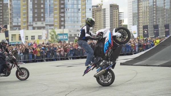 Yekaterinburg, Rusland-augustus 2019: Motorrijders doen trucs op freestyle show. Actie. Professionele motorrijders voeren stunts op de achtergrond van de menigte van mensen achter het hek — Stockfoto