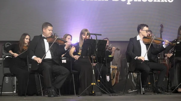 Yekaterinburg, Russia-agosto 2019: Orchestra suona violini sul palco. Azione. Orchestra con giovani musicisti professionisti che suonano violini si esibisce all'evento sul palco — Foto Stock
