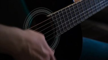 Evde akustik gitar çalan bir adam, yakın plan. Kavram. Gitar çalan bir adamın yakın çekimi.