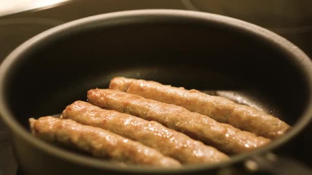 Close-up de salsichas de carne sendo fritas em uma panela de ato de fritar. Conceito. Vista de perto de linguiças que fritam-se em uma panela. Panela com óleo sobre um fogão a gás — Vídeo de Stock