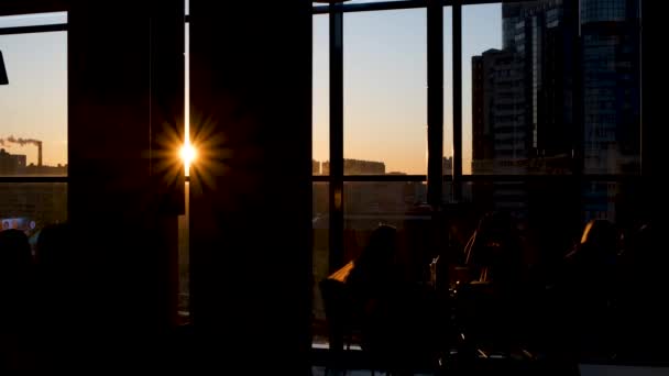 Shadows of people sitting in cafe on background of sunlight. Concept. Beautiful view of silhouettes of people sitting in cafe on background of bright rays of sun — Stock Video