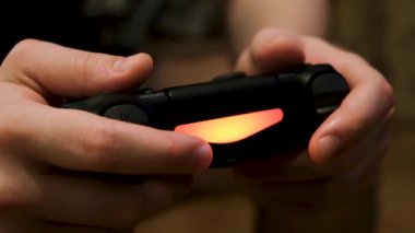 Erkek eller joystick 'i tutuyor, konsolda video oyunları oynuyor, eğleniyor. Kavram. Oyun sahasındaki düğmelere, oyun bağımlılığına ve ev eğlencesi konseptine....