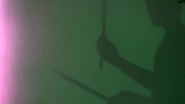 Vue latérale de la silhouette du jeune batteur avec bâton de tambour sur fond mural vert. Concept. Ombre masculine feignant de tambour sous la lumière au néon des lampes, de la musique et du concept d'art . — Video