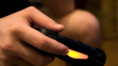 Erkek eller joystick 'i tutuyor, konsolda video oyunları oynuyor, eğleniyor. Kavram. Oyun sahasındaki düğmelere, oyun bağımlılığına ve ev eğlencesi konseptine....