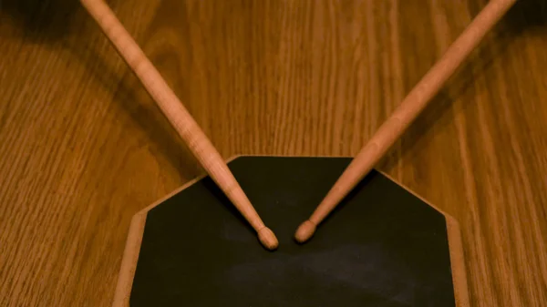 Gros plan d'un homme ou d'une femme pratiquant sur un tampon à tambour avec des pilons sur fond de table en bois. Concept. Une personne s'entraîne pour battre le rythme . — Photo