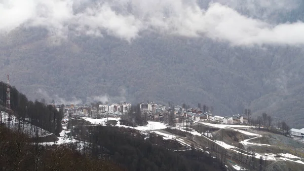 Вид с воздуха на зимний сосновый лес и туман, покрывающий горные склоны в зимний сезон. Запись. Маленький городок в горах . — стоковое фото