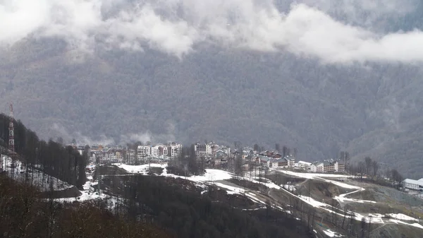 Aerial view of winter pine tree forest and fog covering mountain slopes in winter season. Stock footage. Small town located in mountains. — ストック写真