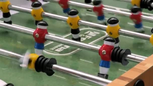 Detailní záběr fotbalové stolní hry se zeleným polem a barevnými hráči plastového fotbalu. Záběry ze skladu. Close up of plastic table football game, volný čas koncept.