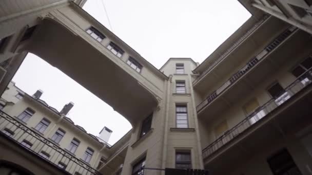 Bottom view of beautiful courtyard of residential building. Journey. Modern architecture of residential building with transition on background cloudy rainy sky — Stock Video