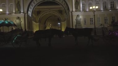 Akşamları tarihi binanın arka planında atları olan arabalar. Yolculuk. Tarihi mimari binaların önünde at arabası sürmek turistler için bir eğlence.