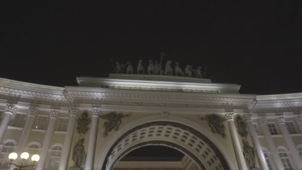 Bågformad passage av historisk byggnad på natten. Resan. Bottenvy över fasaden av historisk byggnad med välvd passage och skulpturer på bakgrunden av natthimlen — Stockvideo