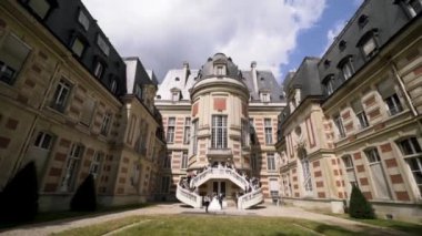 Gorgeous wedding being celebrated in a beautiful castle. Action. Group of people standing on the stairs ready for shooting on a background of the castle.