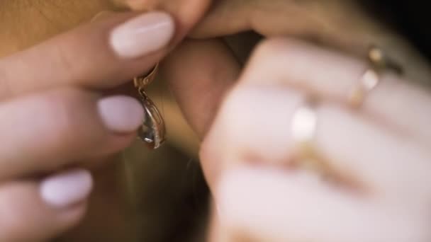 Beautiful woman puts on beautiful earrings. Action. Close up of woman hands touhing her earring with diamonds, jewelry concept. — Stockvideo