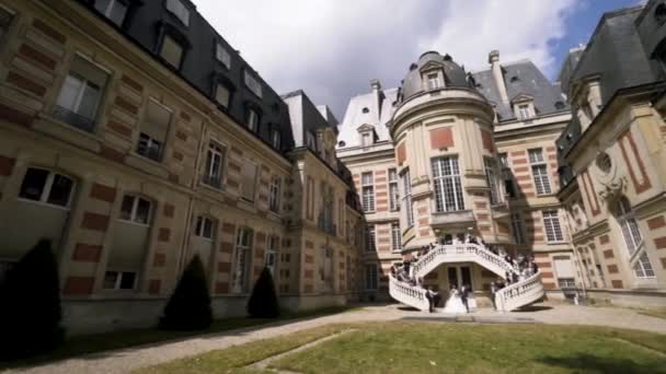 Gorgeous wedding being celebrated in a beautiful castle. Action. Group of people standing on the stairs ready for shooting on a background of the castle. — Stock video