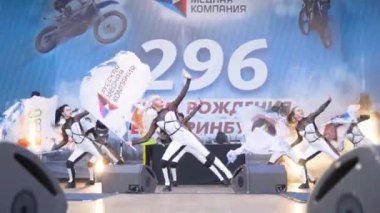 Yekaterinburg, Russia-August, 2019: Beautiful young dancers in white costumes perform on city stage. Action. Bright women dance in modern free style with flags at city festival