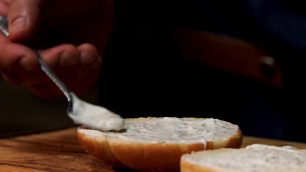 Preparing delicious burgers process, close up of male chef putting white mayonnaise sauce on a hamburger bun. Stock footage. Gastronomy concept. — 비디오