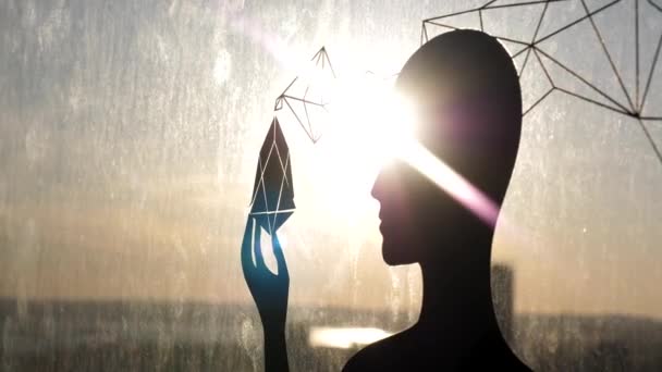 Silhouette féminine noire contre fenêtre en verre avec un objet étrange à la main. Images d'archives. Le soleil brille à travers la forme féminine, le troisième œil et le concept d'illumination de l'âme . — Video