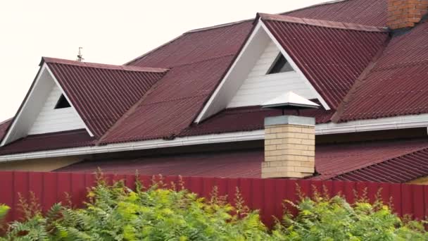 Tetto moderno rivestito con piastrelle di colore rosso su sfondo cielo grigio, materiali di copertura e concetto di costruzione di edifici. Filmati delle scorte. Facciata casa moderna . — Video Stock