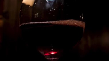 Close up of wine glass with alcoholic beverage inside. Stock footage. Wine glass with red sparkling drink poured into it.