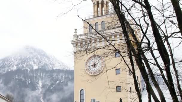 Kaplica kościelna z zegarem na ścianie wieży ze śnieżnym szczytem górskim na tle. Materiał filmowy. Architektura starego europejskiego miasta. — Wideo stockowe