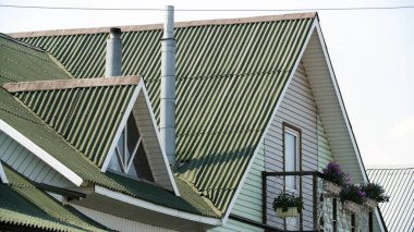 Gri gökyüzü arka planında yeşil renkli fayanslarla kaplı modern çatı, çatı malzemesi ve inşaat konsepti. Stok görüntüleri. Modern ev cephesi.