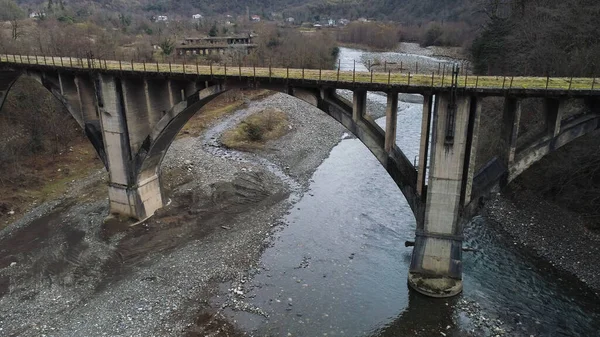 Béton vieilli mousseux pont rural sur la rivière étroite automne froid. Fusillade. Octobre journée nuageuse dans les montagnes boisées, vue aérienne . — Photo