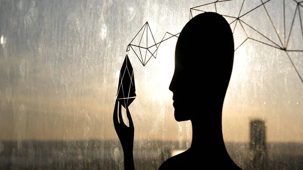 手に奇妙なオブジェクトを持つガラス窓に対する女性の黒のシルエット。ストック映像だ。女性の形、第三の目と魂の悟りの概念を通して輝く太陽. — ストック写真