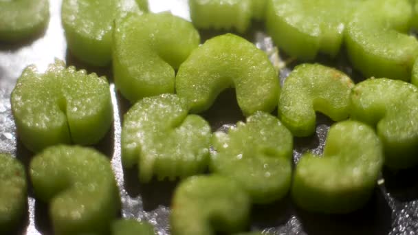 Chopped celery sauteeing on a black frying pan, healthy vegan food concept. Stock footage. Close up of pieces of green fresh celery on oily pan surface background. — Stockvideo