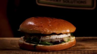 Ev yapımı lezzetli hamburgeri ahşap masaya, gastronomiye ve yemek pornosu konseptine yakın. Stok görüntüleri. Etli, peynirli, marullu ve soğanlı sulu sandviç..