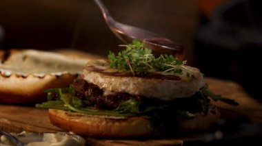 Male chef preparing burger at the restaurant kitchen. Stock footage. Close up of male hands adding wine and cranberry sauce to the tasty delicious beef burger, foodporn.
