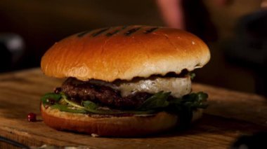 Homemade grill beef burger or sandwich with camembert cheese, cranberry sauce and berries, fresh green mustard sprouts. Stock footage. The perfect lunch of western cuisine, foodporn.