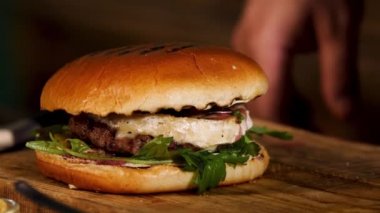 Close up of amazing big tasty fresh meat sandwich with fresh vegetables and herbs, foodporn concept. Stock footage. Tasty burger with beef cutlet.