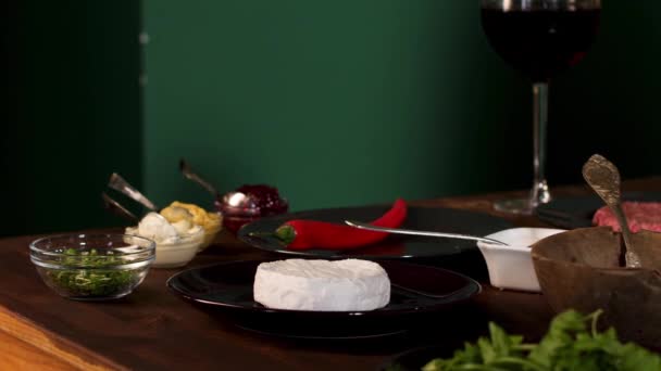 Close up of the ingredients and different sauces on the wooden table. Stock footage. Cheese camembert, red hot chili pepper , and greenery for burger preparation. — 비디오