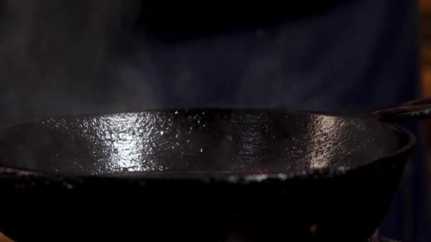 Fermer la sauce à frire masculine et ajouter du sucre ou du sel dans une casserole en fer noir. Images d'archives. Processus de préparation des aliments au restaurant .