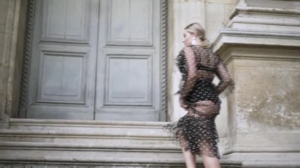 Erstaunlich sexy blondes Plus-Size-Model in schwarz gepunktetem transparentem Kleid und Unterwäsche die Treppe des historischen Gebäudes hinauf. Handeln. Positives Konzept.