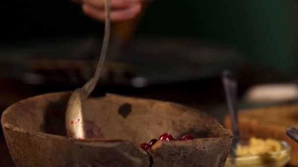 Vecchia ciotola di legno con mirtilli rossi in piedi sul tavolo su sfondo stanza scura. Filmati delle scorte. Primo piano della mano maschile prendendo un cucchiaio di bacche fresche rosse per la cottura . — Video Stock