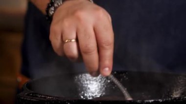 Close up of male hands cooking sauce in the iron frying pan. Stock footage. Chef preparing delicious sauce for the dish, western cuisine concept.