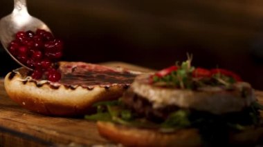 Homemade grill beef burger or sandwich with camembert cheese, cranberry sauce and berries, fresh green mustard sprouts. Stock footage. The perfect lunch of western cuisine, foodporn.