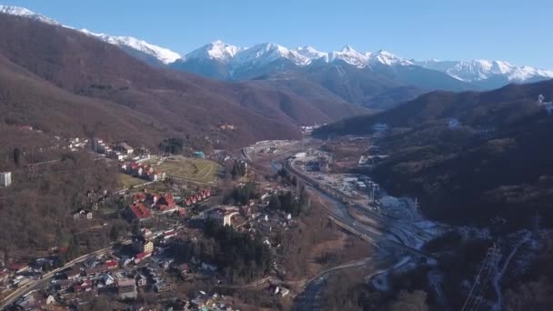 Letecký pohled na zimu Rakousko vesnice v údolí v blízkosti malebné slunné Alpy hory. Klip. Létání nad silnicemi a domy na venkově obklopený vysokými zalesněnými kopci. — Stock video