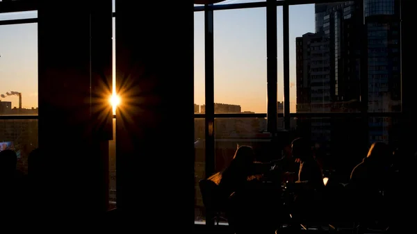 Shadows of people sitting in cafe on background of sunlight. Concept. Beautiful view of silhouettes of people sitting in cafe on background of bright rays of sun — Stock Photo, Image