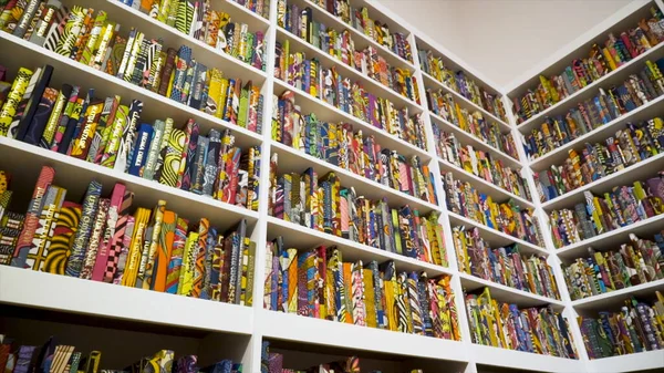 Βιβλιοθήκη με πολλά πολύχρωμα βιβλία σε σχέδια. Πάμε. Βιβλία με πολύχρωμα σχέδια καλύμματα τοποθετούνται κομψά στα ράφια των μεγάλων rack — Φωτογραφία Αρχείου